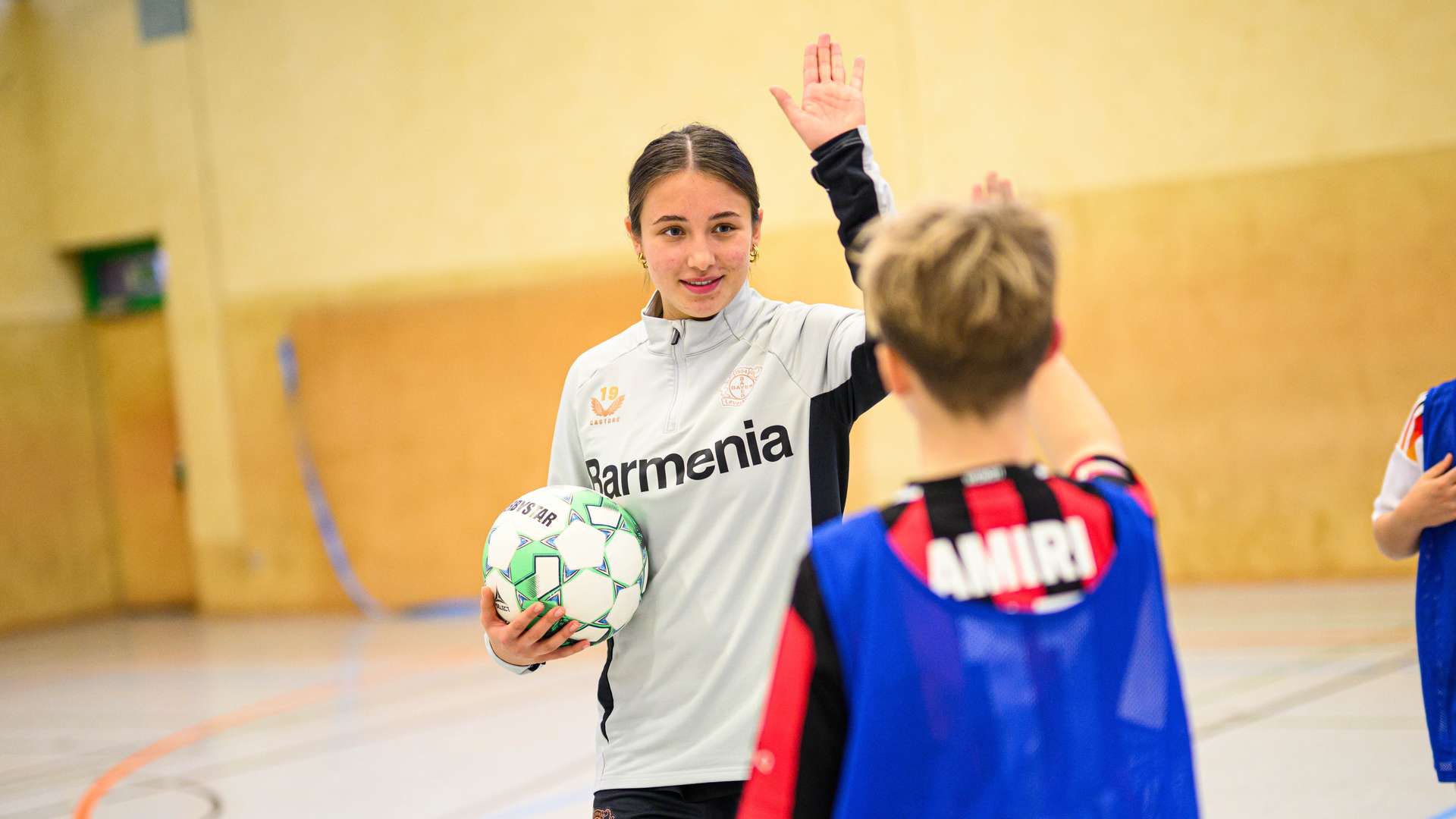 Loreen Bender klatscht mit einem Schüler ab