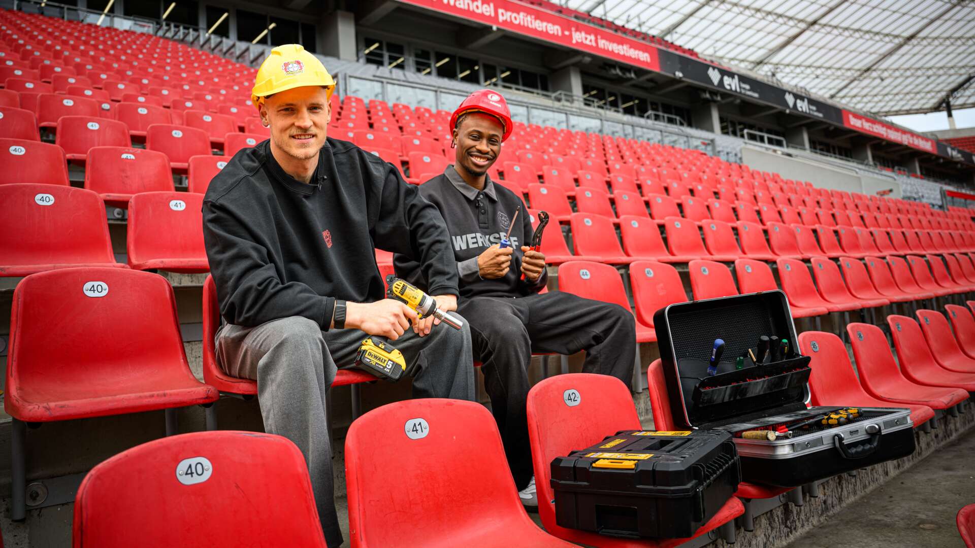 Niklas Lomb und Nathan Tella montieren die Stadionstühle ab